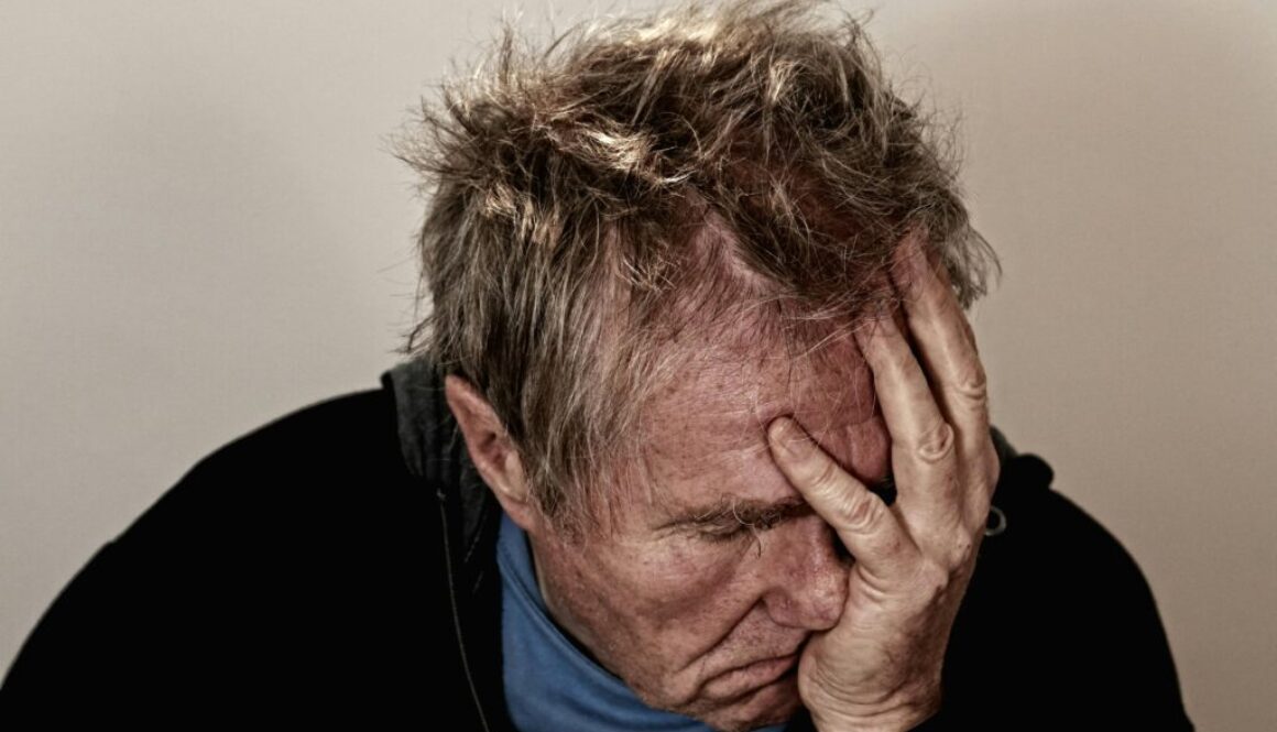 A middle-aged man holding his head in exhaustion, representing brain fog and cognitive fatigue—a common reason to search for the best brain health supplements after 45.