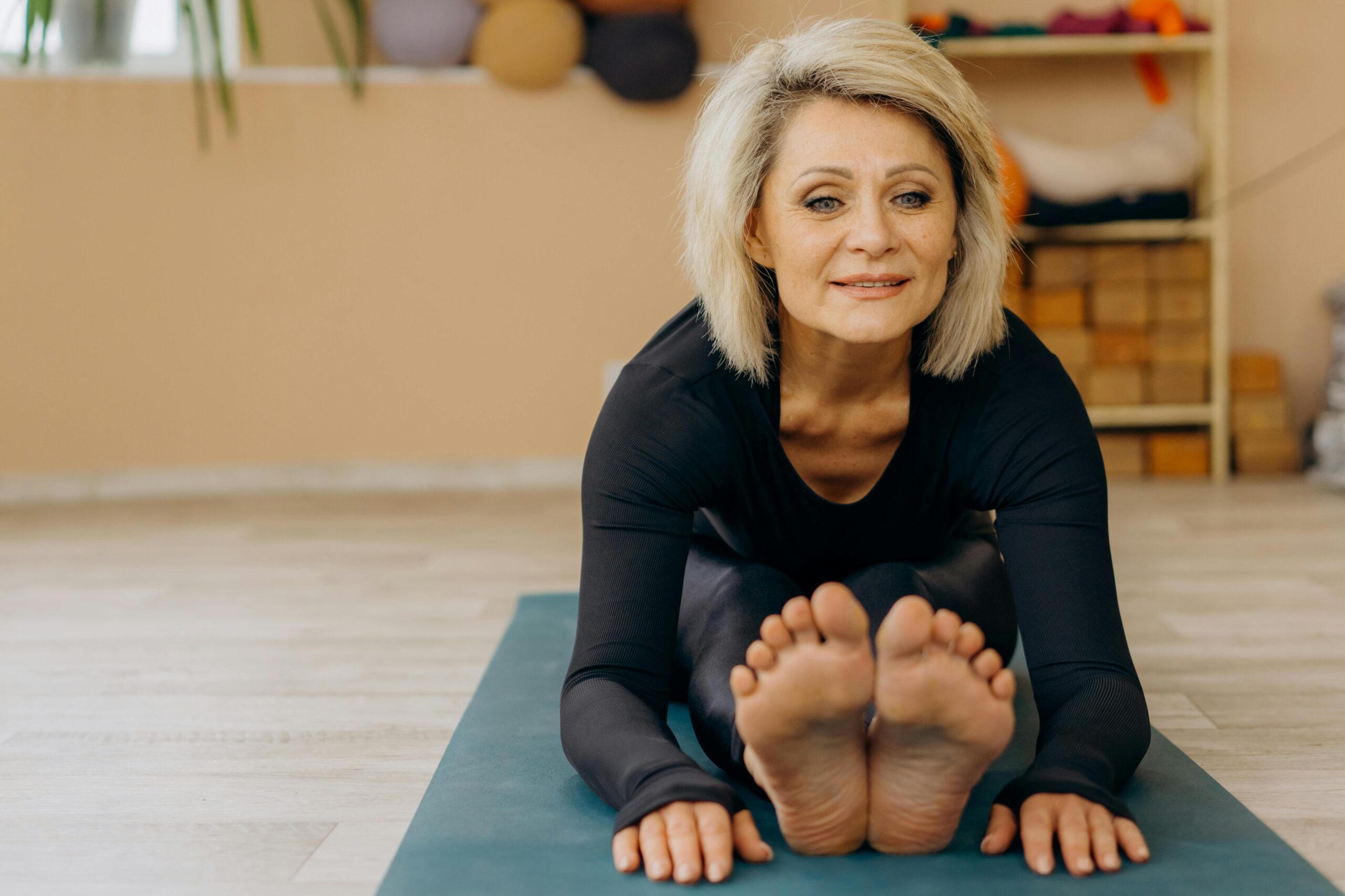 A healthy mature woman practicing a seated forward fold yoga stretch, representing the vitality supported by the best longevity supplements backed by research.