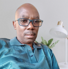 Portrait of the founder of otienoamonde.com wearing glasses and a striped polo shirt in a professional indoor setting.